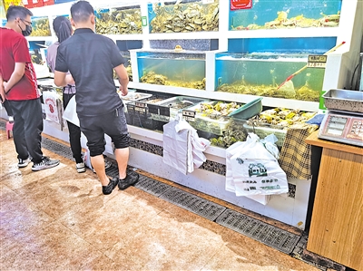 海鲜销售摊位前挂着三种塑料袋，其中有厚塑料袋。