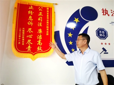     4月12日17时30分，西吉县兴隆镇司法所，马生强向记者讲述锦旗背后的调解故事。