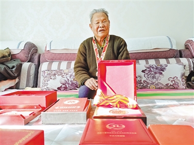 <p>　　芦计昌展示勋章和荣誉证书。</p>