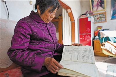 <p>　　吴秀珍老人翻看上世纪八十年代通义村土地记录本。</p>