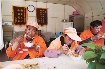    环卫工人师爱林（中）和同事们一起吃营养午餐。