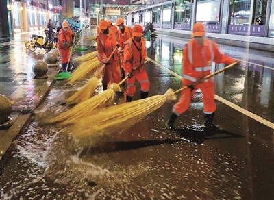环卫工人集中清扫道路积水和淤泥。   本报记者    高晓刚    摄