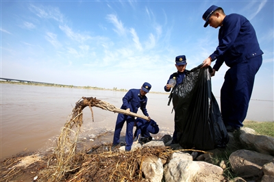 5月1日下午，消防员捡拾清理黄河边的垃圾和漂浮物。