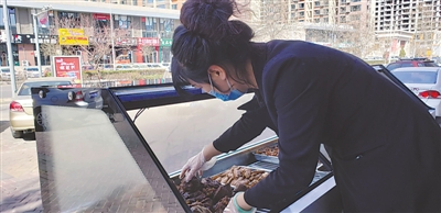 <p> 王海春在整理店外摊点熟食。</p>