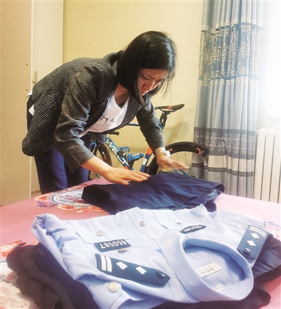     马文丽含泪整理丈夫的警服。  本报记者 王若英   摄