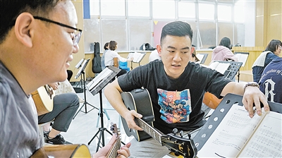 “青年夜校”吉他老师周晓瑞给学员讲解曲谱。