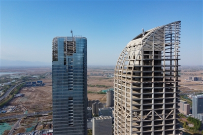 4月18日，在银川阅海湾中央商务区，“双子塔”正在建设。据了解，银川绿地中心（“双子塔”）项目分为南北两个塔楼，其中地下3层、地上66层，总建筑面积近30万平方米。按照银川市相关要求，该项目将于6月20日前完成北塔幕墙工程、亮化工程及室外景观工程，6月30日前完成南塔幕墙南、北立面施工的80%，尽快完成南塔幕墙封闭。本报记者  季正  摄