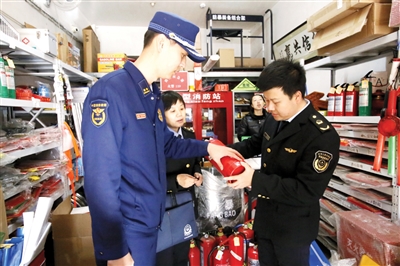 执法人员检查灭火器是否为“三无”产品。