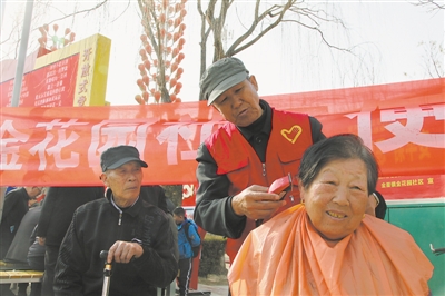 <p>　　仇良明（左）在为社区居民义务理发。</p>