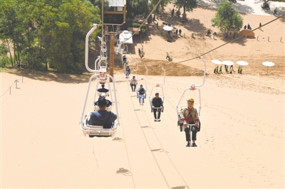 <p>　　在沙坡头景区，游客乘坐滑沙索道，在高空欣赏大漠长河风光。</p>