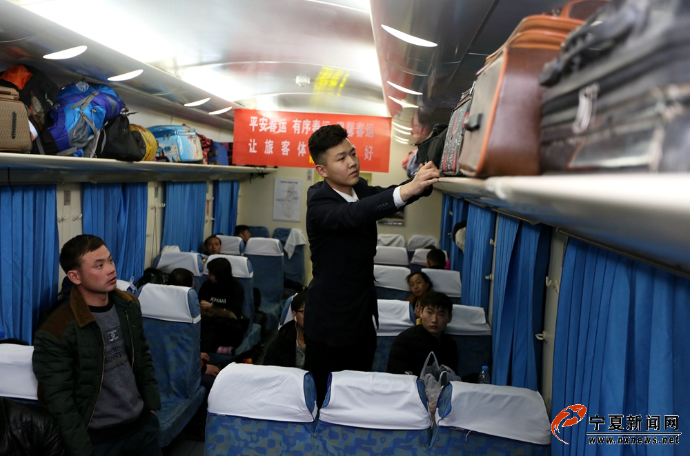 2月13日晚，在由银川至北京的Z275次列车上，列车员李杨正在调整行李架，防止行李掉落砸伤旅客。