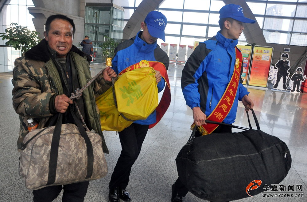 在银川火车站候车大厅，两名志愿者看到一位大哥提着沉重的行李，立马上前接过其手中的行李。