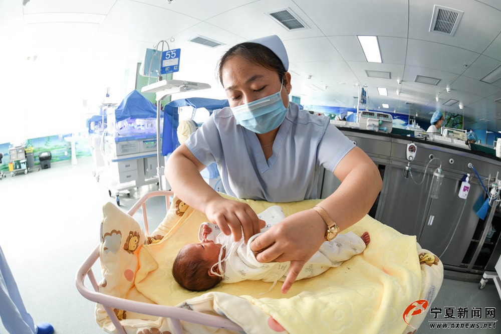 新生儿痊愈出院，医护人员为宝宝换上新衣。她们会为这些幼小的生命重新焕发光彩而无比欣喜。