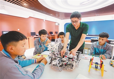 <p>　　福建省泉州市支教教师黄培基（中）在同心县豫海初级中学开办机器人研发兴趣小组。　　本报记者　王猛　王洋　摄</p>